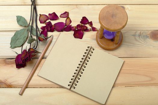 Empty notebook and dry roses with pencil on old wood, eco concept background for valentine.