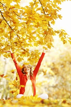 Happy woman in autumn park drop up leaves