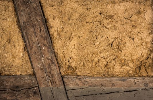 Clay house wall, with details on the wooden beams and the mixture of mud and straw, perfect as background