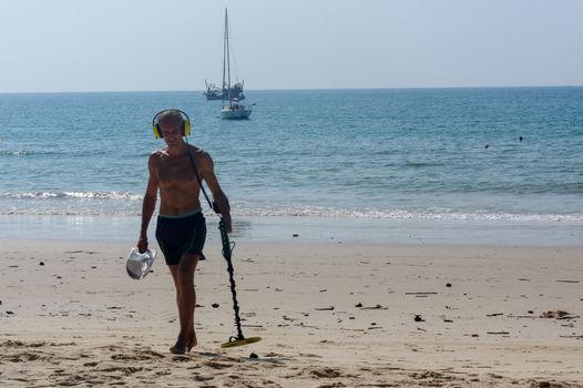 a treasure hunter with Metal detector on the beach