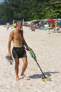 a treasure hunter with Metal detector on the beach