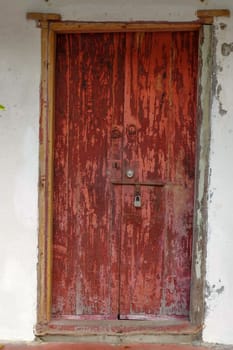 a closed old red wooden door. Mediterranean style exterior.