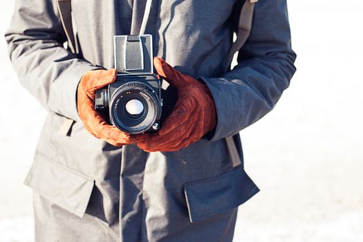 Man hold in hand a vintage old camera on the seashore background