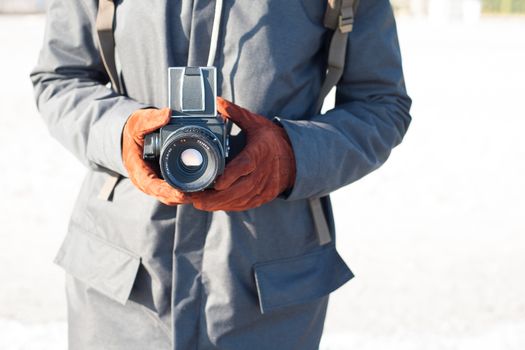 Man hold in hand a vintage old camera on the seashore background