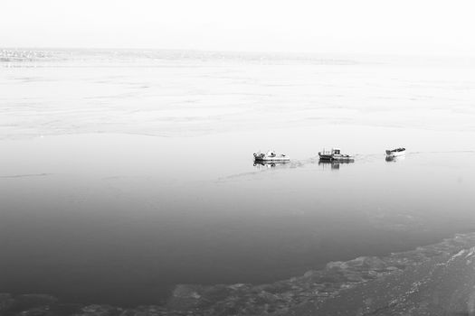 A few small ships in the winter sea near coast black and white photo
