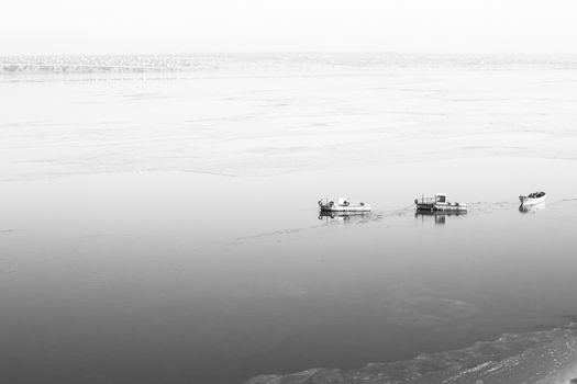 A few small ships in the winter sea near coast black and white photo