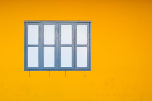 Close Dark Blue Window on Grunge Yellow Concrete or Cement Wall Background as Interior or Exterior Design Concept