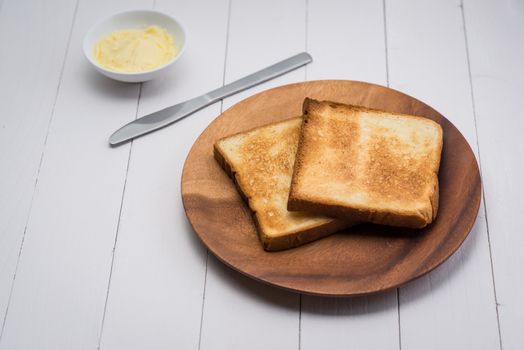 Close-up of slice of toast bread with butter on wood table