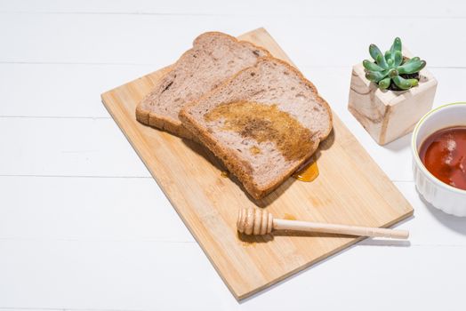 Close-up of slice of toast bread with honey on wood table