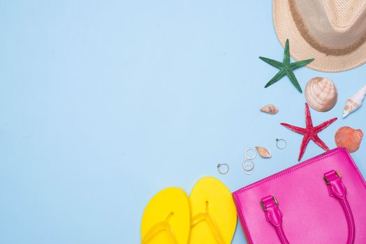 Summer concept. Pink handbag with accessories on light blue background