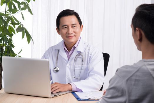 Confident asian male doctor discussing diagnosis with patient in office