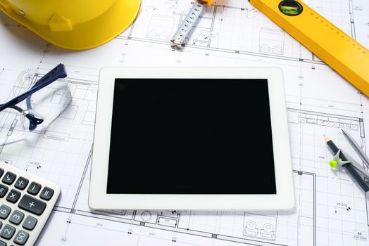 digital tablet with architectural blueprints rolls and tools