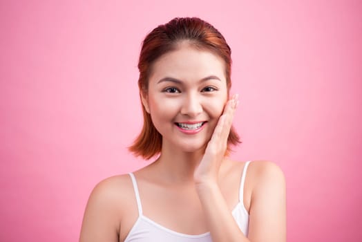 Portrait of a beautiful smiling young woman with natural make-up. Skincare, healthcare. Healthy teeth. Studio shot. Isolated on Pink Background.