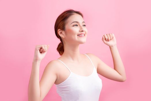 Portrait of a carefree young asian woman smiling with arms raised