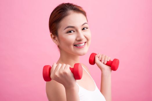 Woman Lifting Weights. Fitness woman lifting weights smiling happy on pink background.