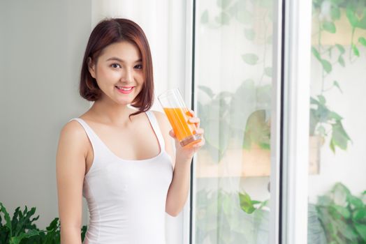 Portrait of a beautiful young asian woman having orange juice.