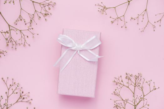 Gift box tied with pink ribbon and white flowers for mothers day