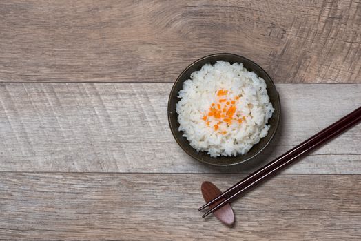 Boiled rice in a bowl on wooden table.