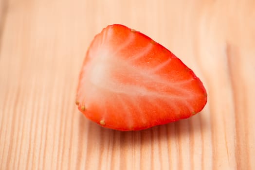Half of strawberry on wooden background.