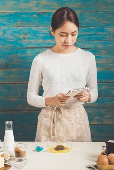 House wife wearing apron making, reading recipes according to the book