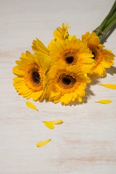 Yellow daisy bouquet on wooden table.