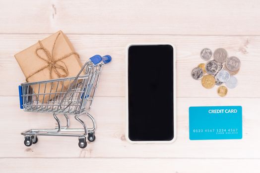 Shopping online concept. Small blue trolley and gadgets on the wooden table.