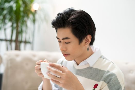 Asian businessman using mobile phone  during coffee break on table in coffee shop