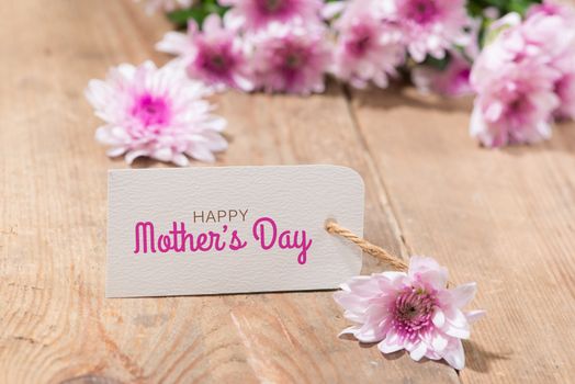 Mothers Day. Tag paper with color flowers on wooden background. Top view. Mock up