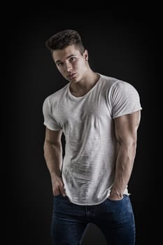 Handsome young muscular man looking at camera in studio shot over neutral background