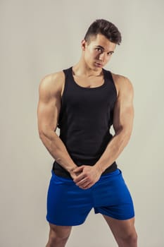 Handsome young muscular man looking at camera in studio shot over neutral background