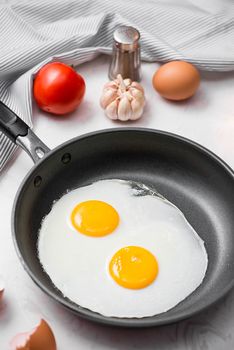 Fried eggs in a frying pan with cherry tomatoes and bread for breakfast