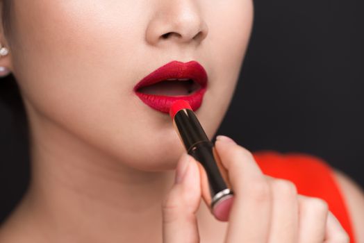 Professional Make-up. Attractive asian model applying red lipstick. 