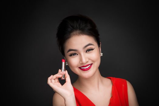 Professional Make-up. Attractive asian model applying red lipstick. 