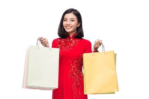 Charming Vietnamese Woman in Red Ao Dai Traditional Dress holding Shopping Bags.
