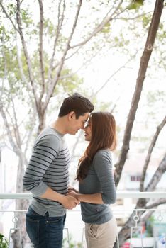 Couple in love sharing genuine emotions and happiness, hugging on the balcony