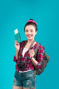 Woman travel. Young beautiful asian woman traveler holding passport and air ticket standing over blue.
