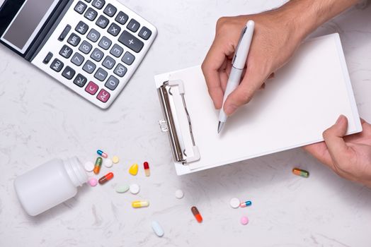 Healthcare costs concept. Opened medicine bottle and spilled out capsules on table.