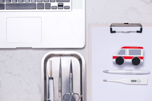 Workplace of a doctor. Laptop, clipboard and other stuff on desk.