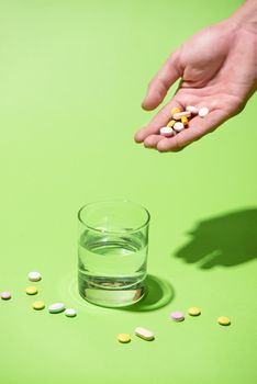 Colored pills in hand with water on blue background.