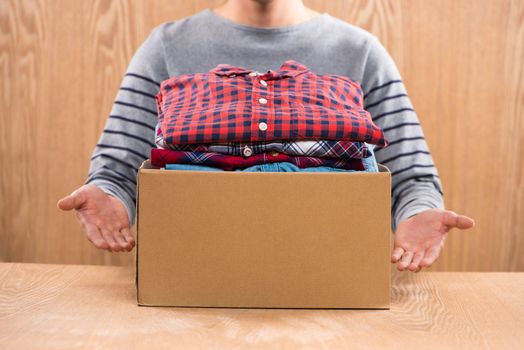 Donation box for poor with clothing in male hands