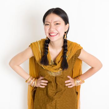 Portrait of beautiful mixed race Indian Chinese female in traditional Punjabi dress smiling, standing on plain white background.