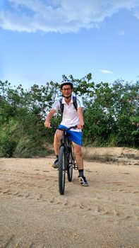 Asian man with mountain bike on rocks. Sport and active life concept.