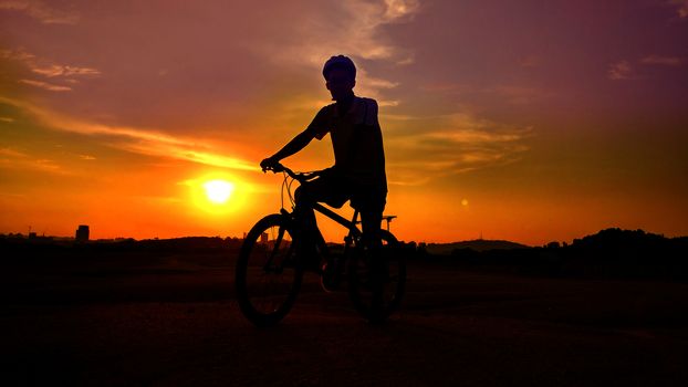 silhouette of the cyclist riding a road bike at sunset