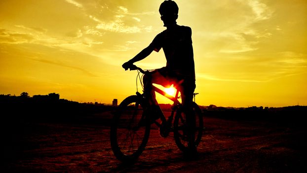 silhouette of the cyclist riding a road bike at sunset