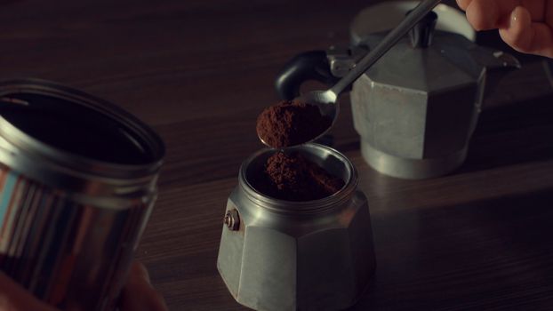 Close up of man's hand pouring coffee in a geyser