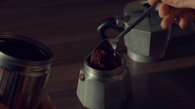 Close up of man's hand pouring coffee in a geyser