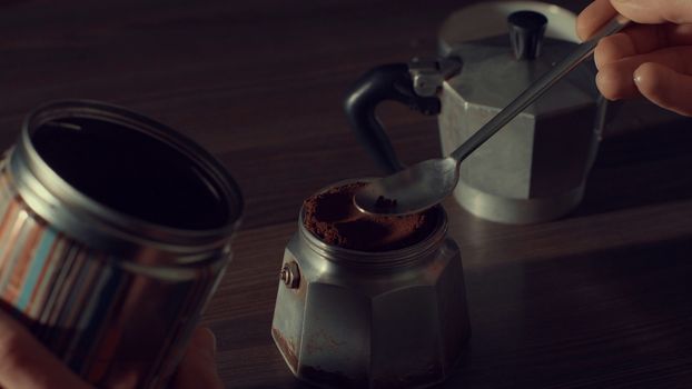 Close up of man's hand pouring coffee in a geyser