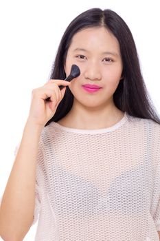 Teenage Asian girl applying makeup with a brush