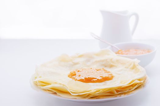 Crispy crepes with apricot jam on a white plate