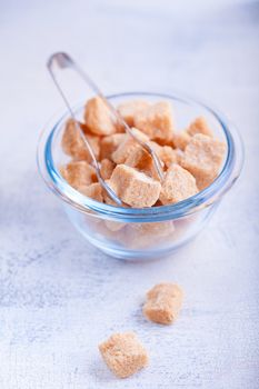 Brown cane sugar cubes in a glass bowl.